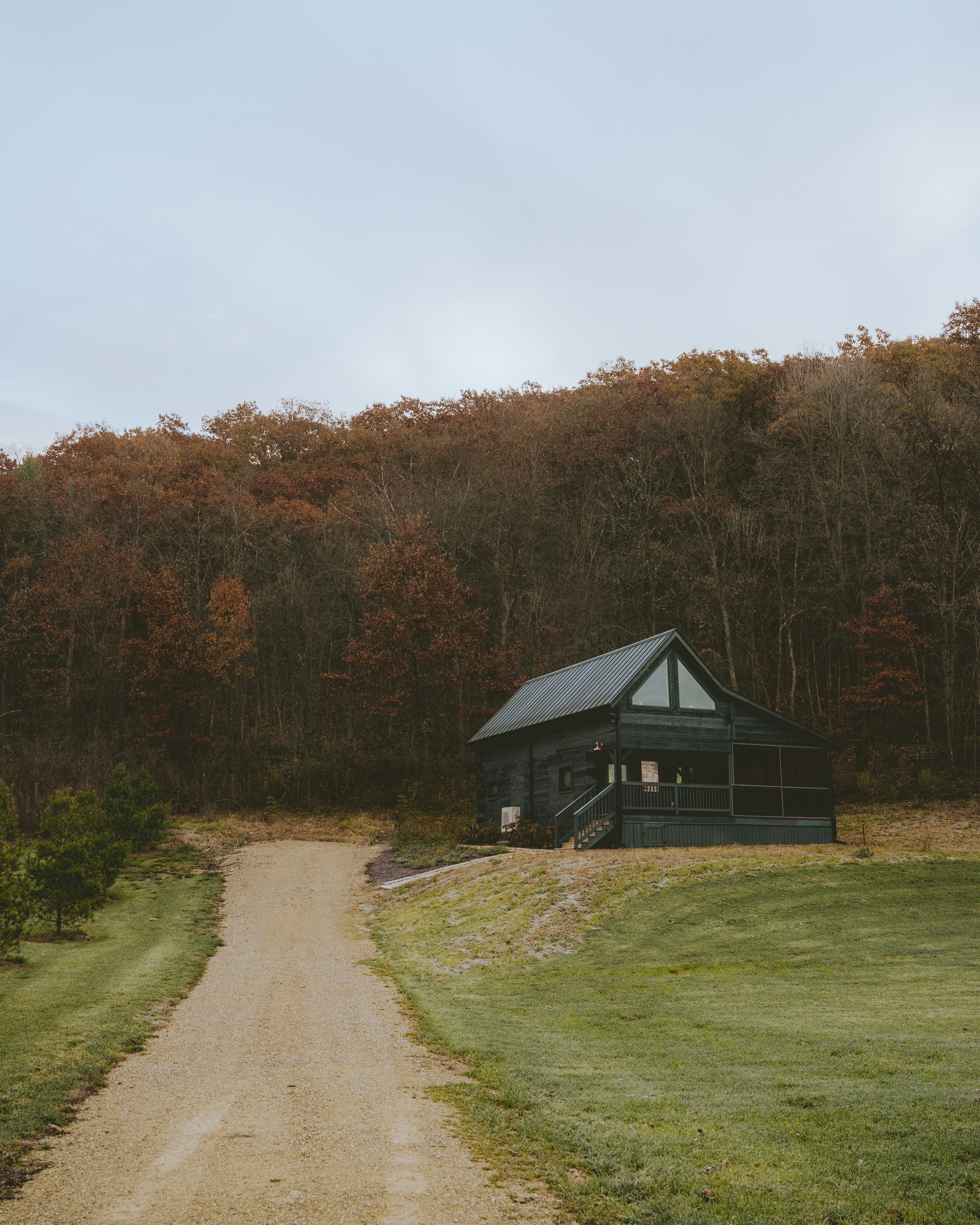 A cabin sits on a rocky hill under a cloudy sky.
