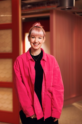 Photo of Emily Allinson smiling at the camera wearing a pink shirt