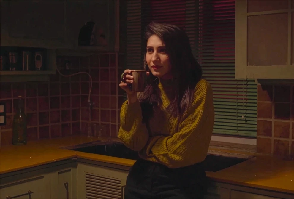 man wearing grey t-shirt standing in front of man sitting on chair