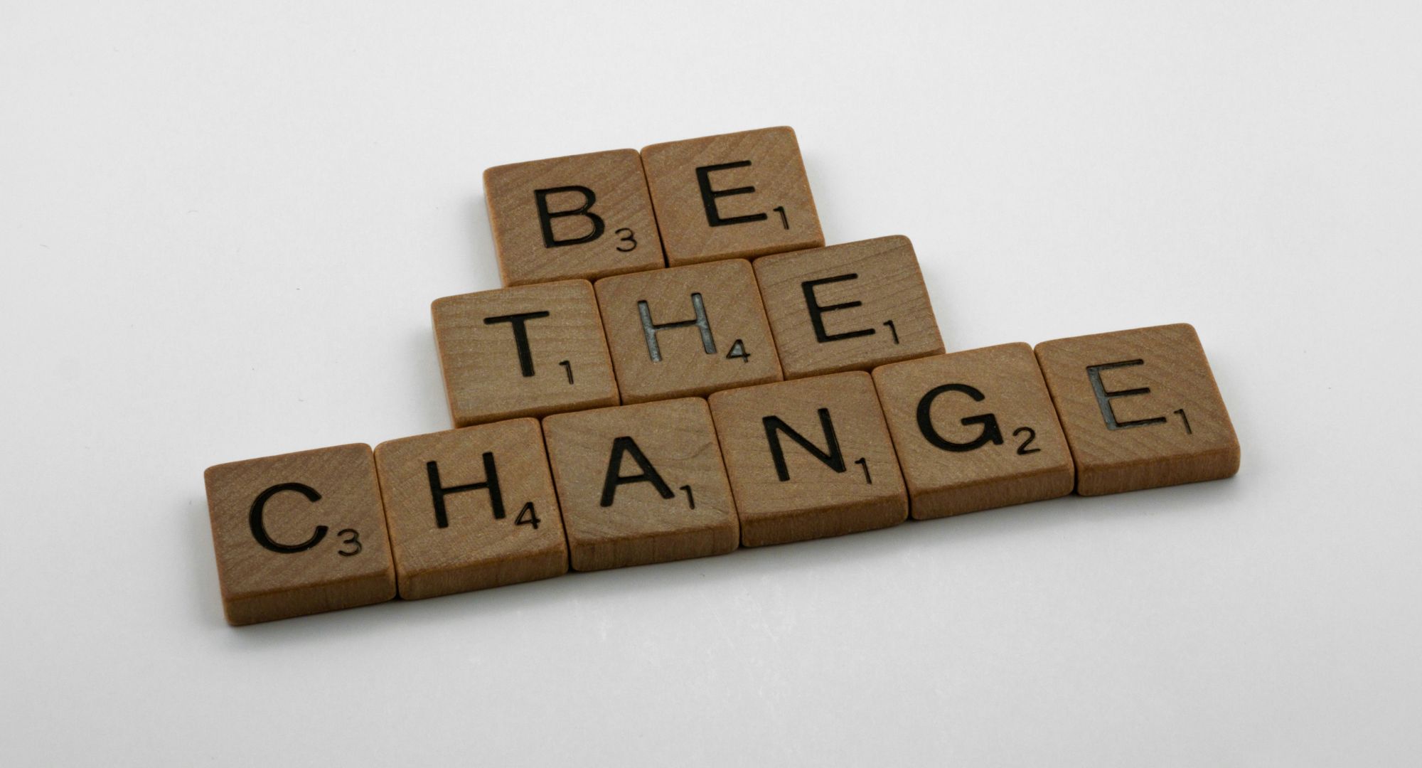 blocos de madeira com letras formando a frase "BE THE CHANGE"
