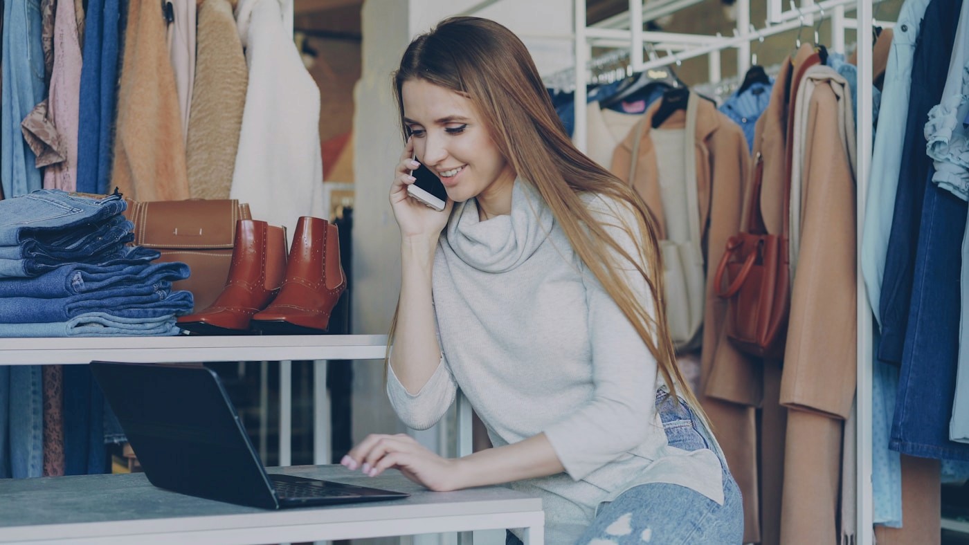 Business owner coordinating customer requests on phone and laptop
