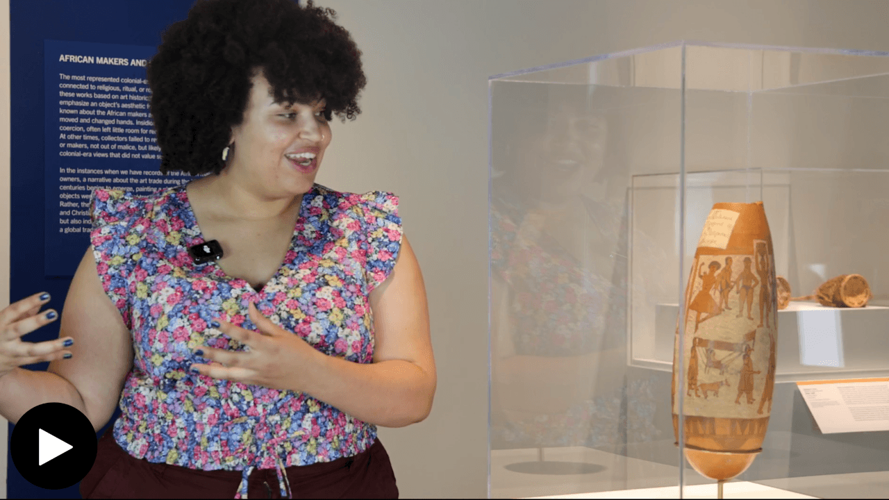 Alana Joy Okonkwo in the Belongings exhibit, looking at the gourd in a glass case.