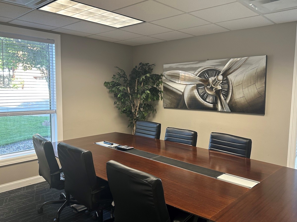 Man with a beard in a dark button-up shirt, smiling while writing in a notebook.