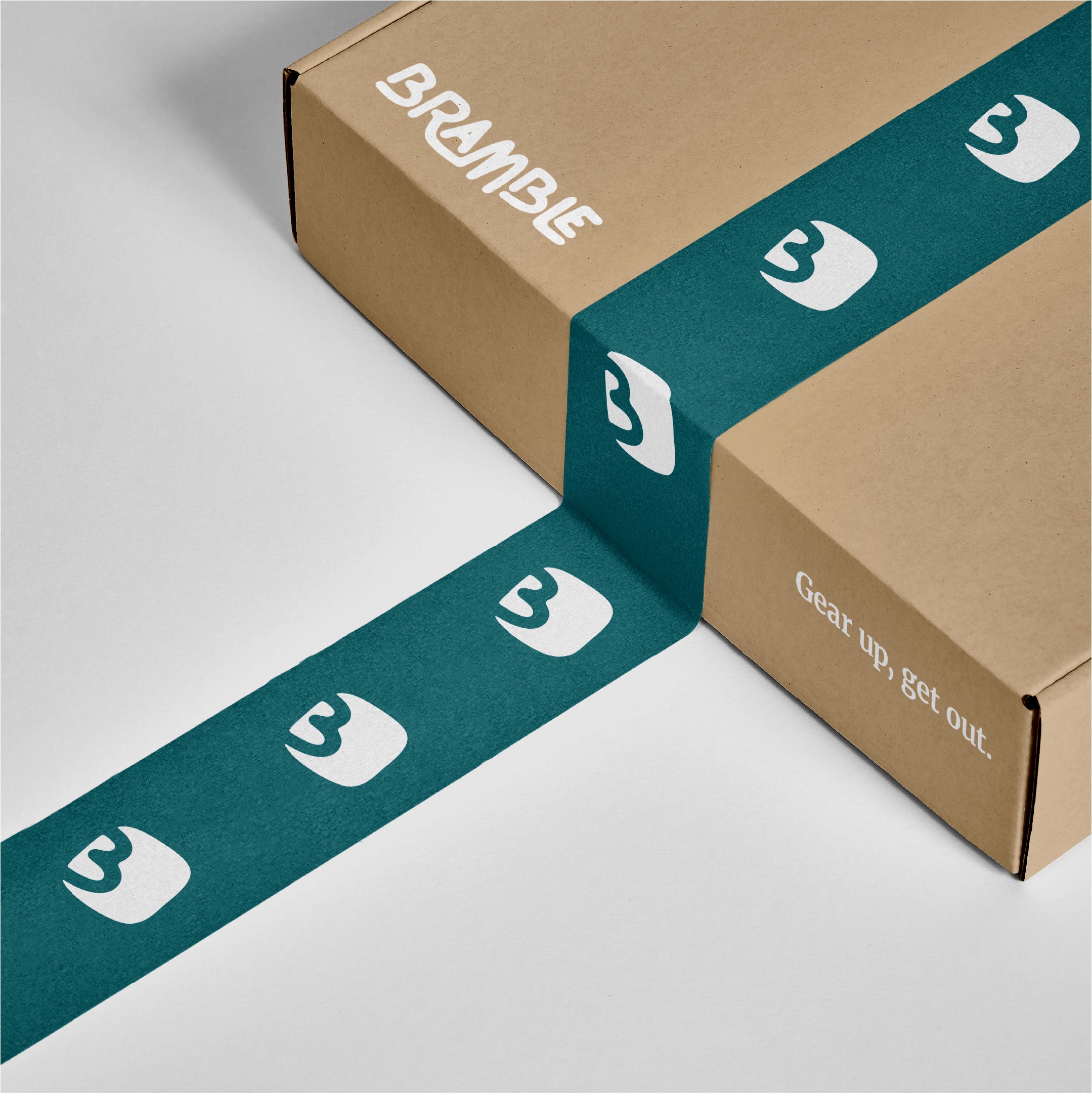 This image features a cardboard shipping box for the outdoor brand Bramble, positioned against a plain white background. The box is secured with a wide, dark teal packing tape that prominently displays a repeating white pattern of the brand's organic "B" logo. The top of the box is printed with the Bramble wordmark in white, while the side features the brand's slogan, "Gear up, get out," in a white serif typeface.