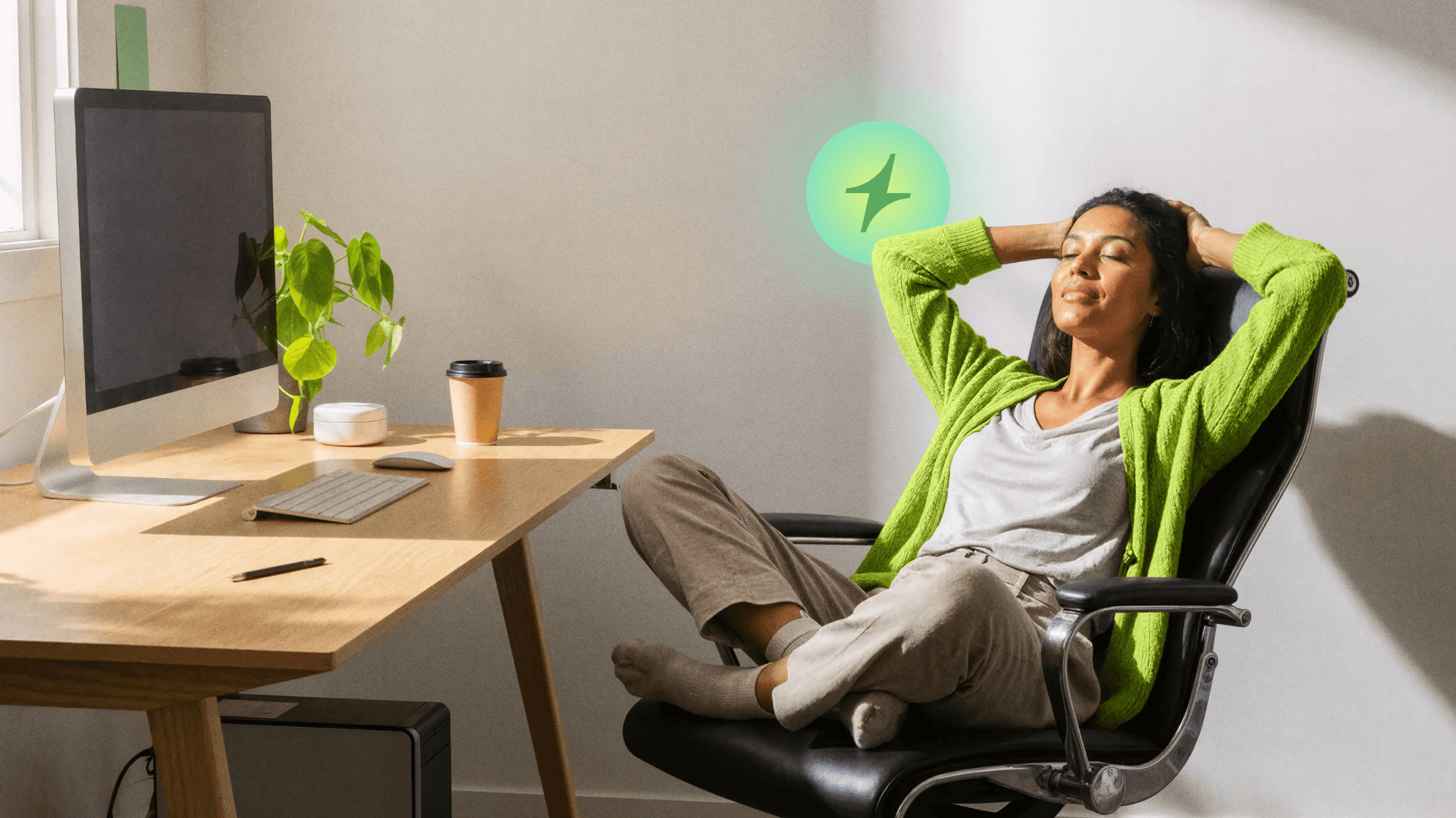 Profissional relaxando em cadeira ergonômica no ambiente de trabalho de clínicas modernas, representando o bem-estar e conforto proporcionado pelas soluções Tivita uma cadeira de escritório reclinável, com os pés cruzados, olhos fechados e mãos atrás da cabeça, relaxando em frente a uma mesa com computador, planta e café, em um ambiente de trabalho iluminado pela luz do sol.