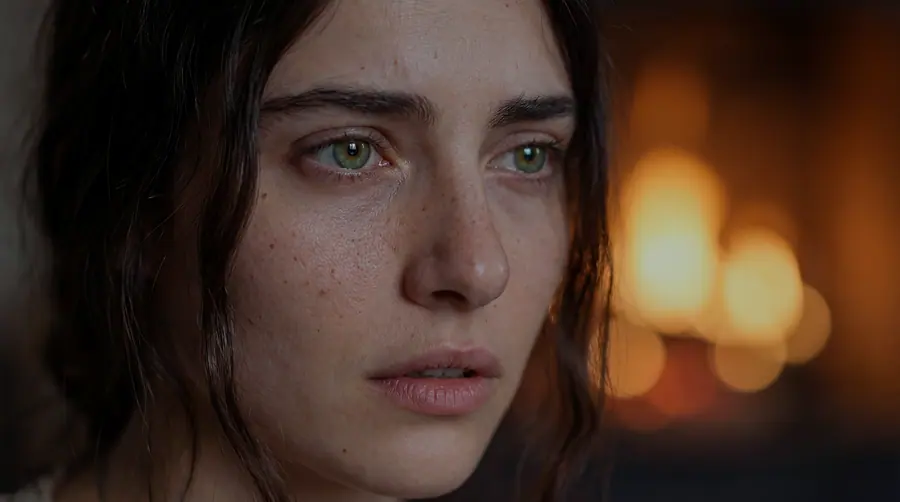 Close-up of a young woman in lamplight, her green eyes in focus