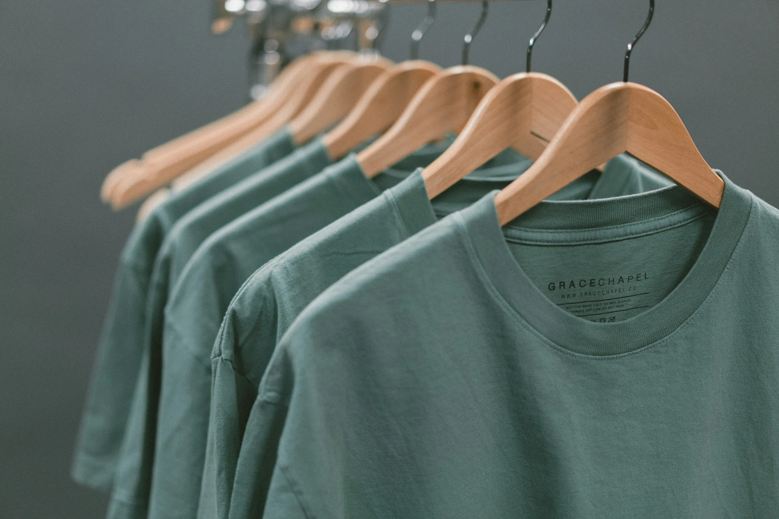 Minimal clothing rack with neutral t-shirts on wooden hangers, modern apparel display