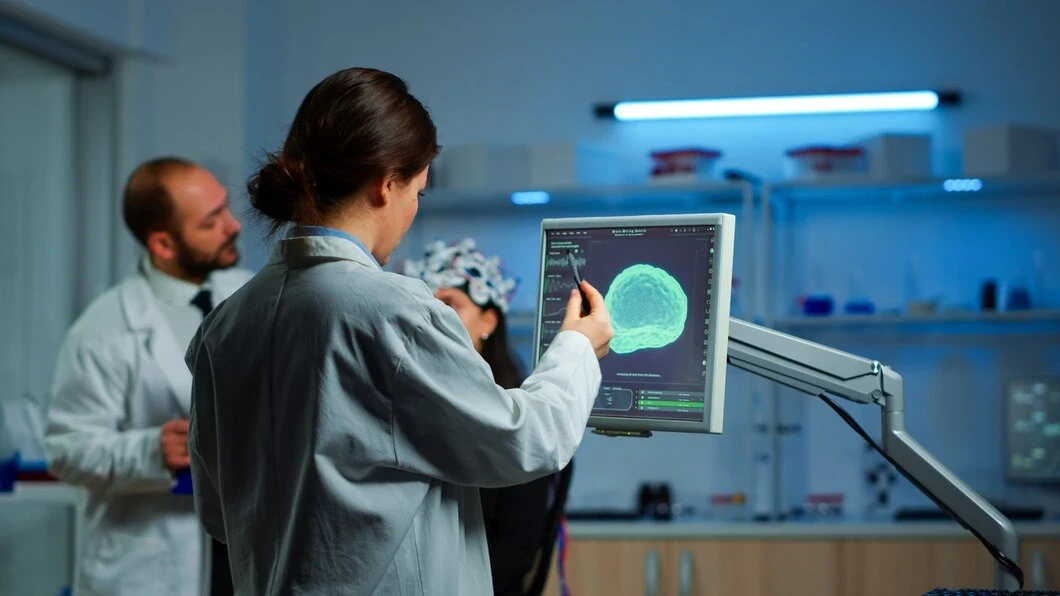 researcher looking monitor analysing brain scan while coworker discussing with patient