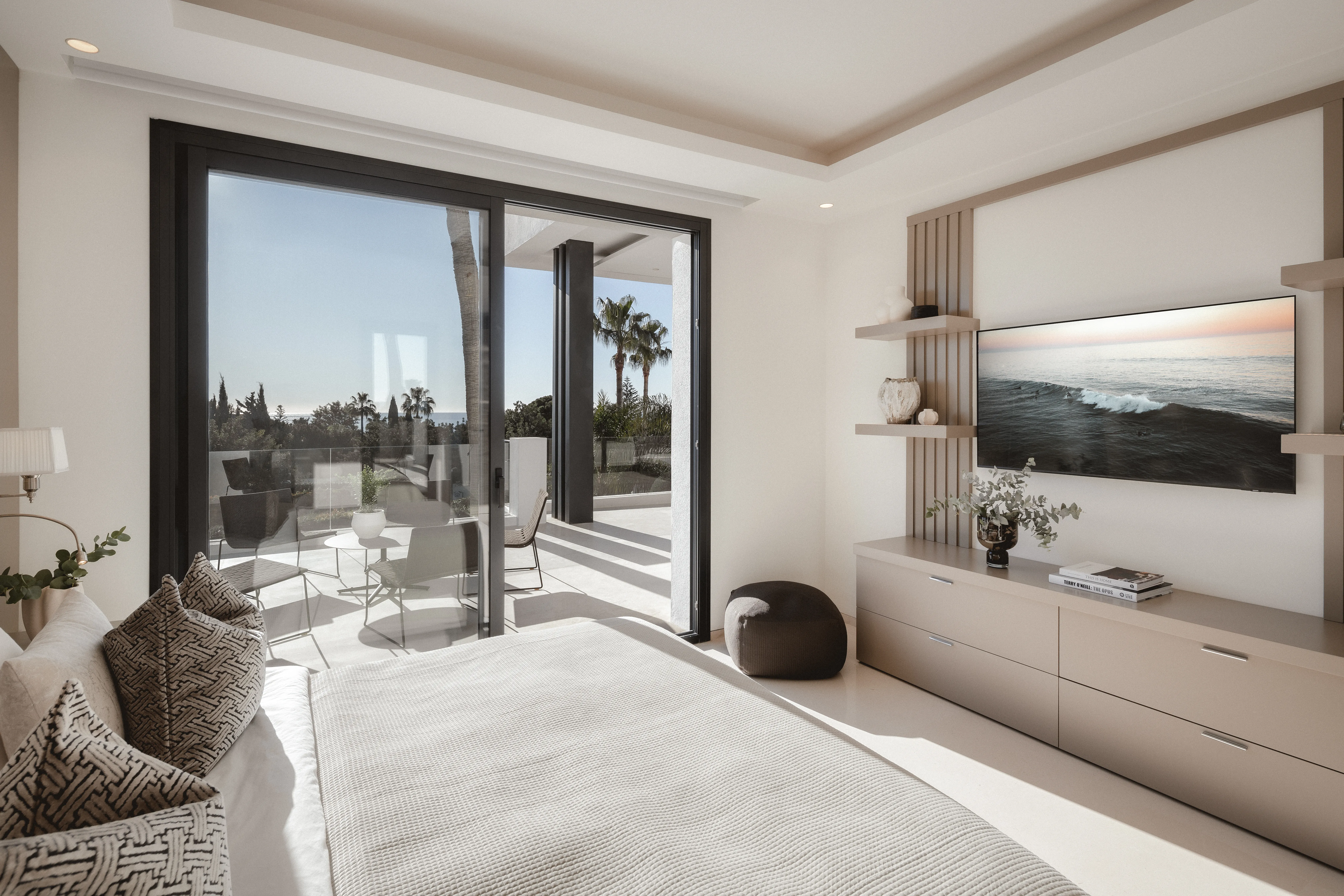 Bright bedroom with floor-to-ceiling windows, natural materials and terrace views.