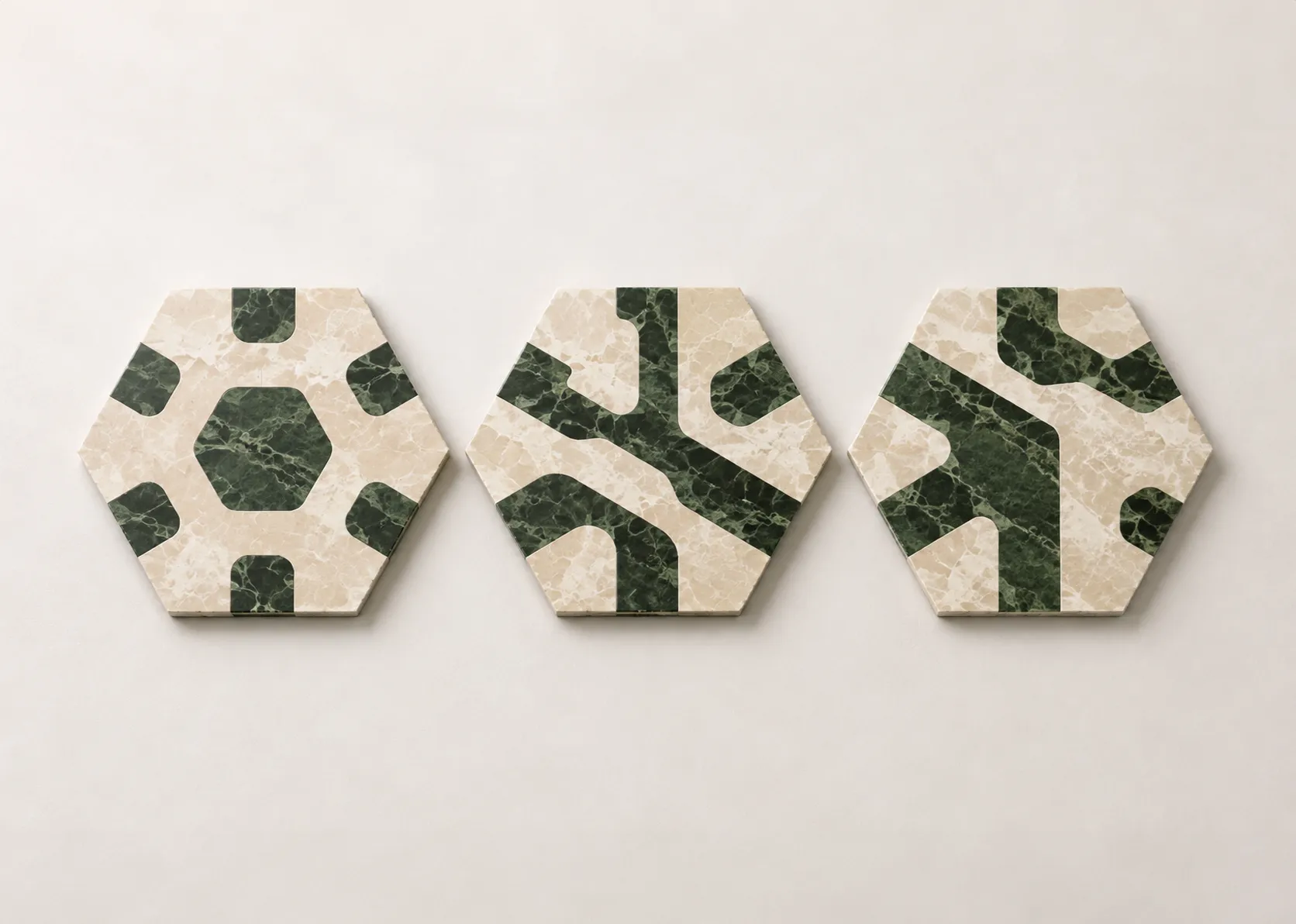 Three hexagonal marble floor tile modules from the Tessera collection, shown side by side in light beige and dark green stone.