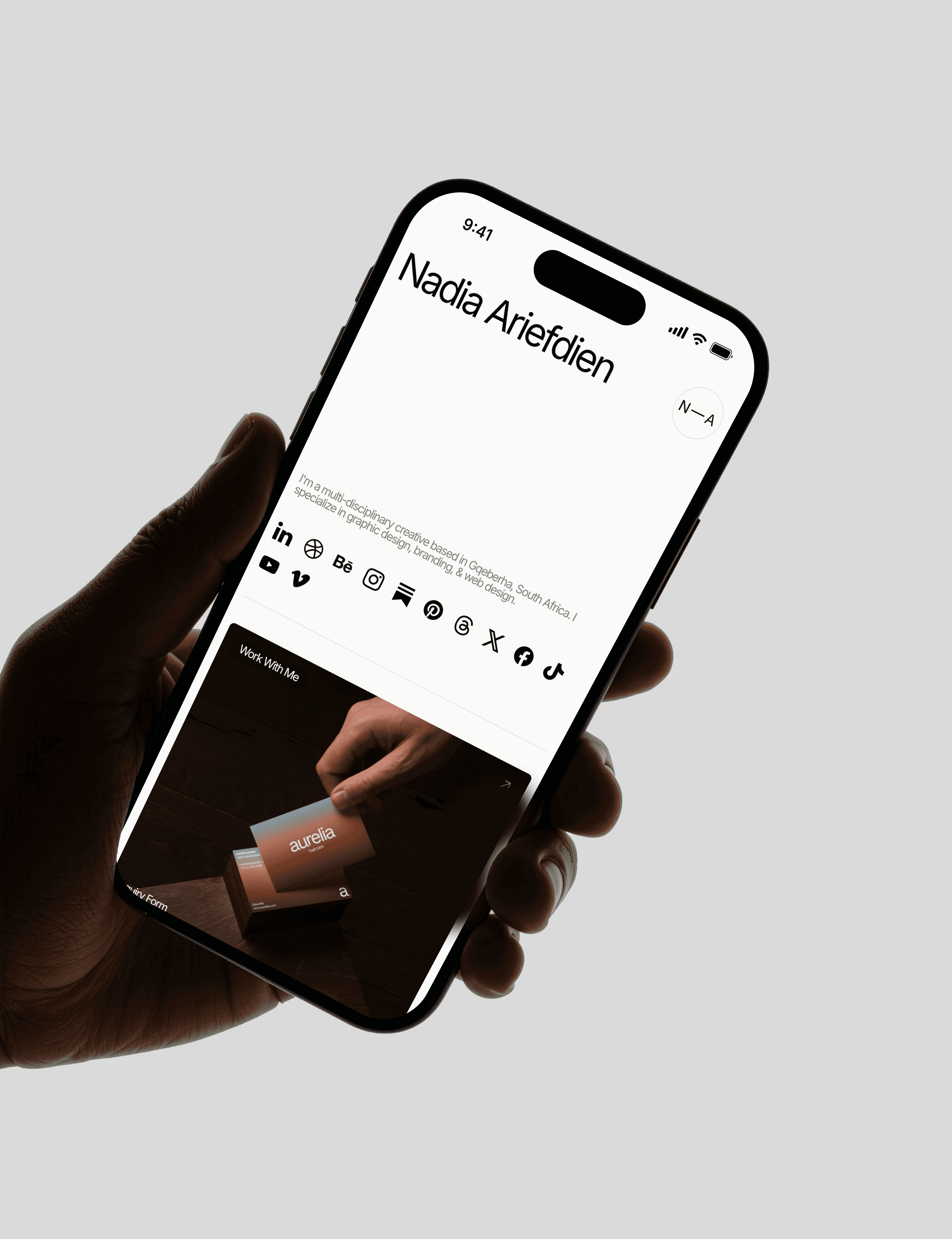 A person's hand holding an iPhone. The screen shows Nadia Ariefdien's link in bio website.