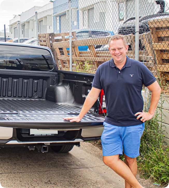 Man leaning on truck tailgate, wearing polo and shorts