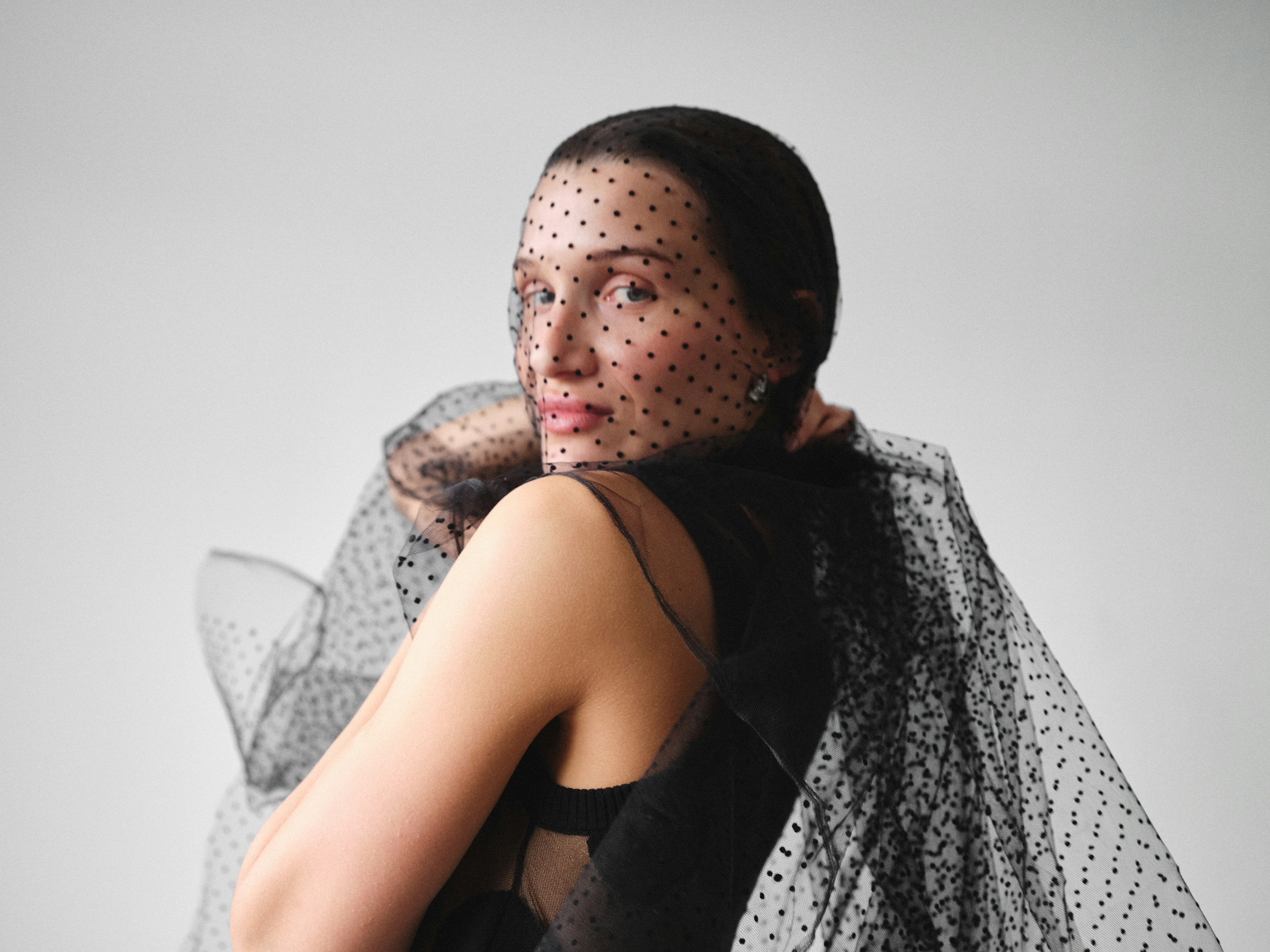 Woman in sheer polka dot veil and black dress
