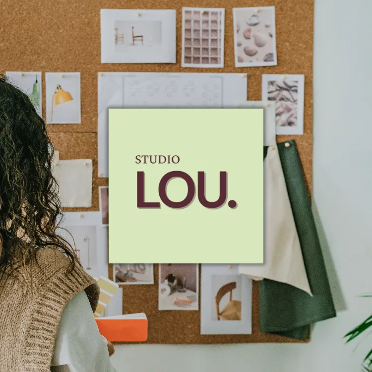 Studio Lou logo overlayed on a photo of an interior designer with a pinboard with fbric samples, drawings, inspiration images and interior design photos.