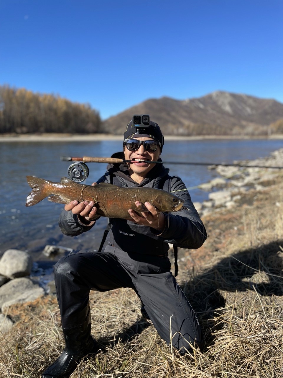 Man fishing in Mongolia holding up a fish