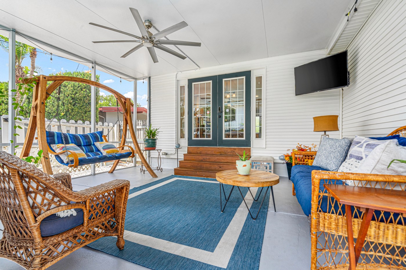 Screened porch with a porch swing, lounge seating and ceiling fan at a St. Petersburg home