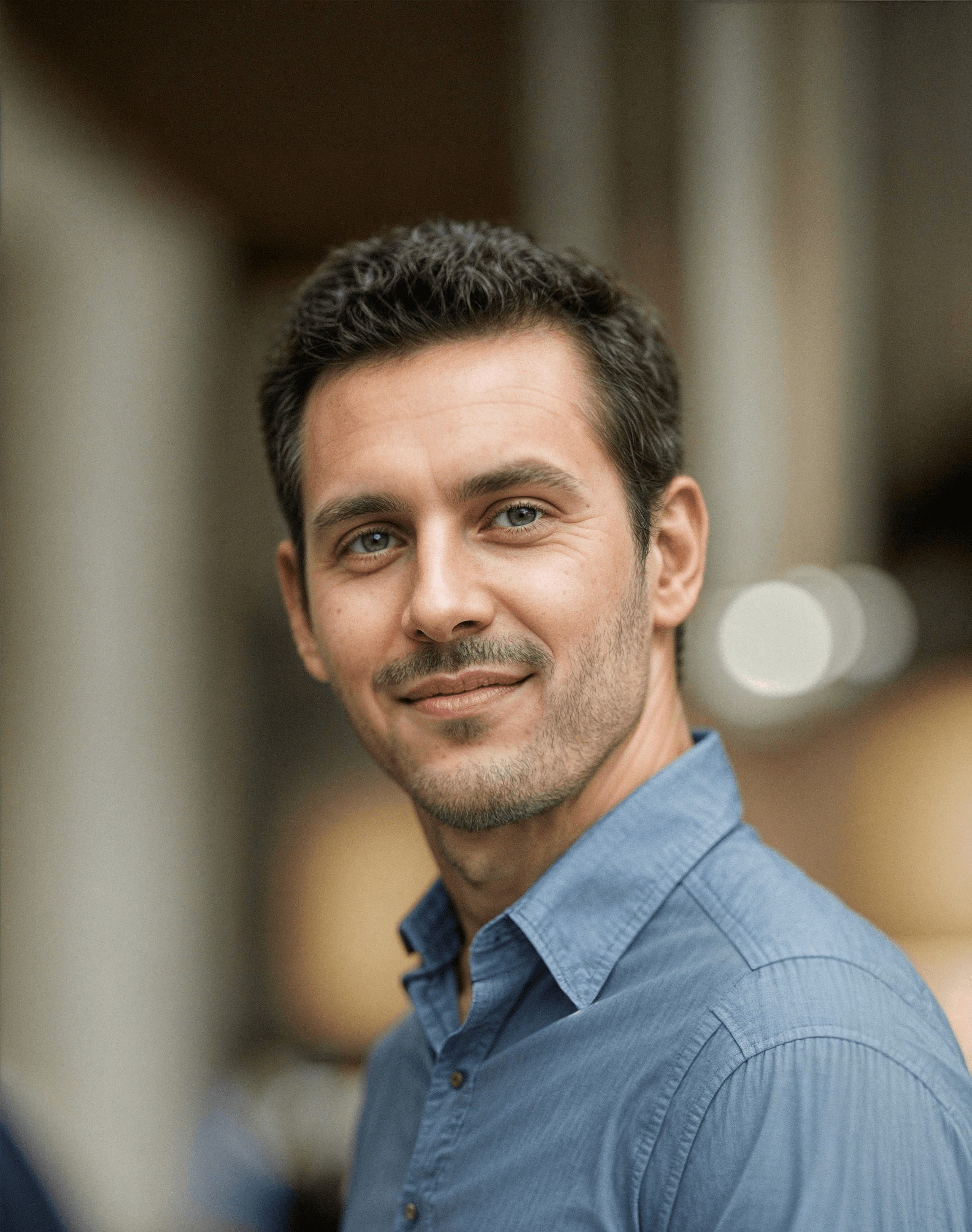 a man in a blue shirt smiling at the camera