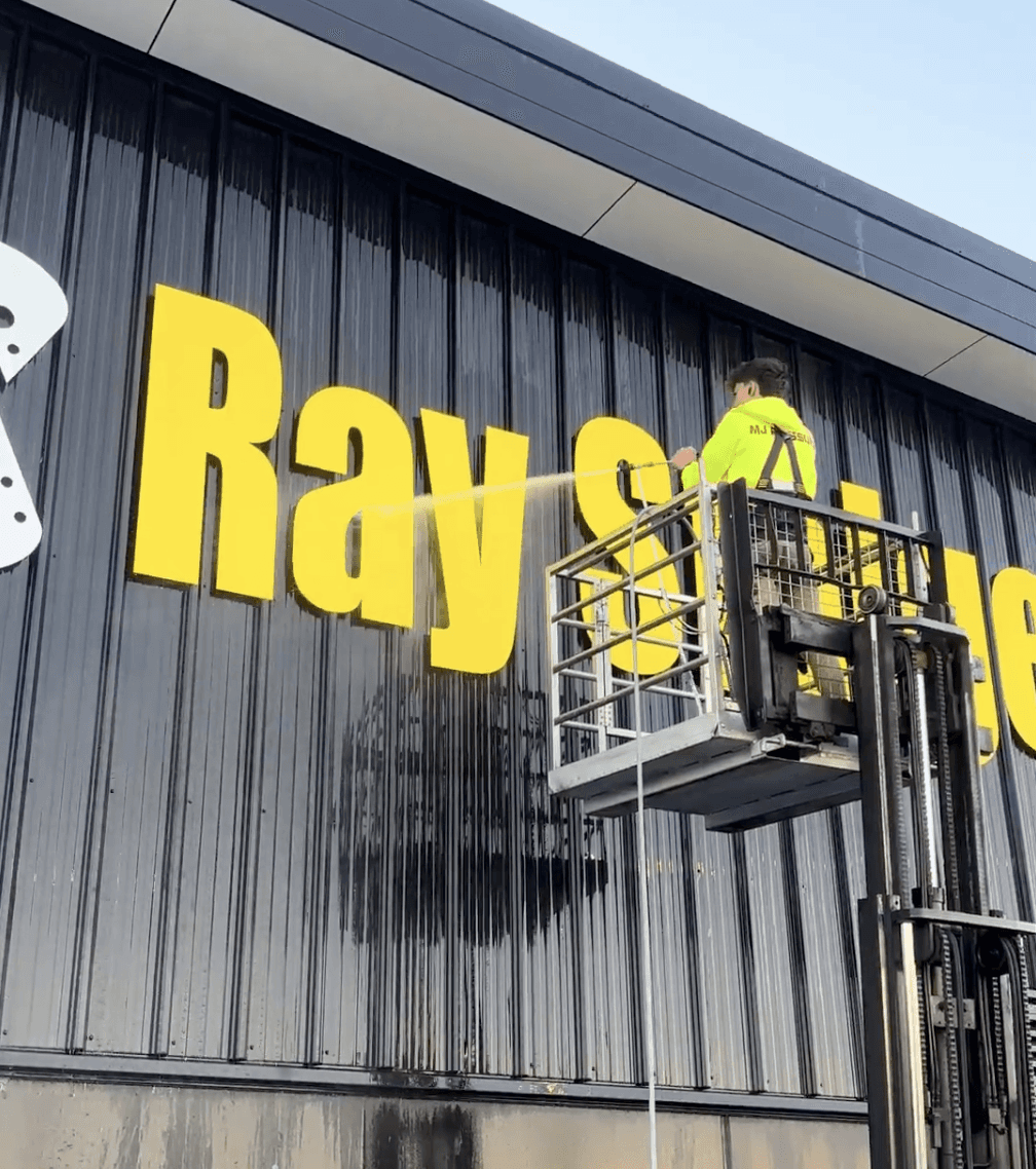 Max soft washing the exterior of a commercial building in Hamilton by MJ Exterior Cleaning