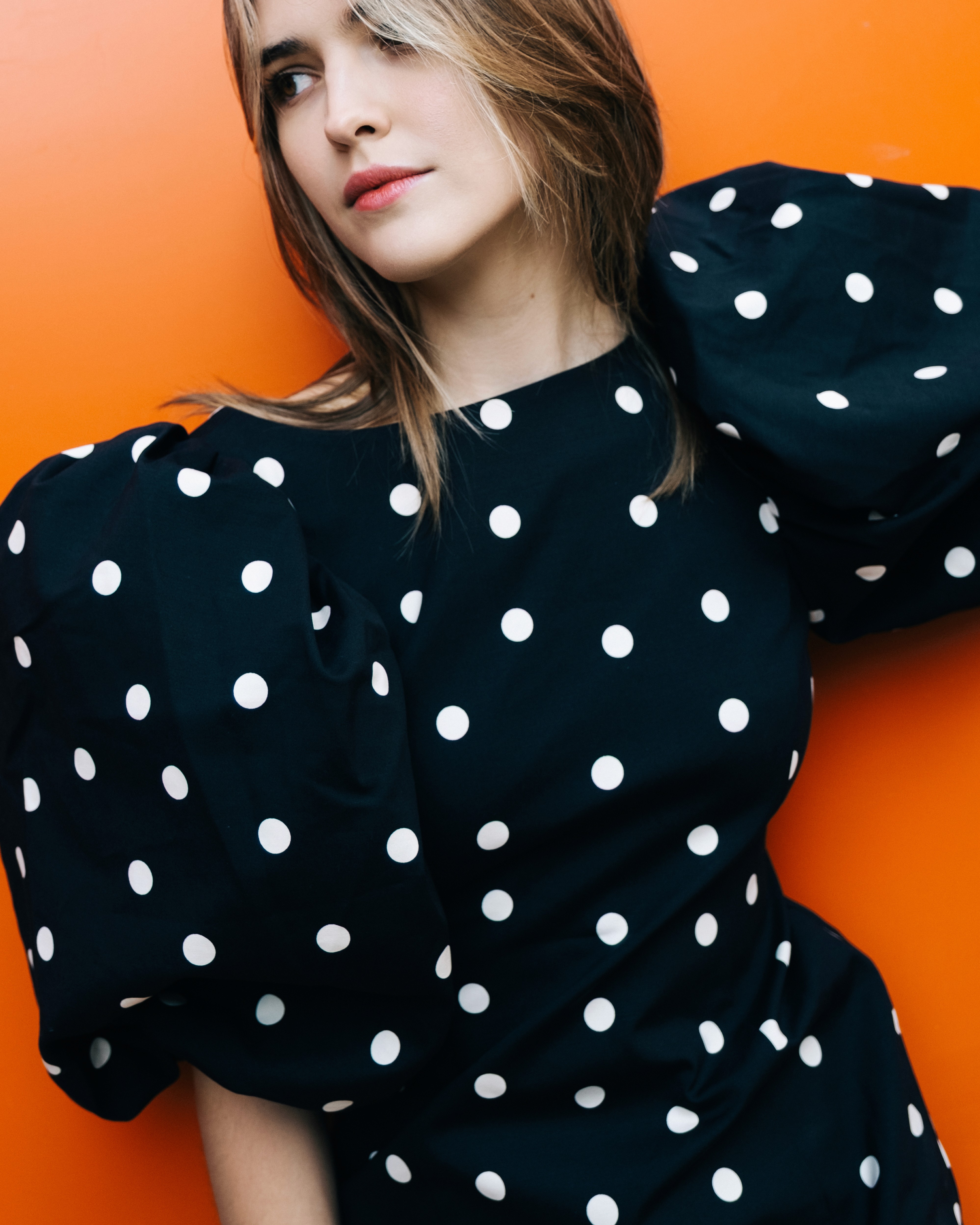 Ania – She Owns the City - portrait against a vivid orange wall.