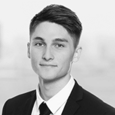 Headshot of employee, Nicolas Wyndham Sich, on a blue tinted, grey background