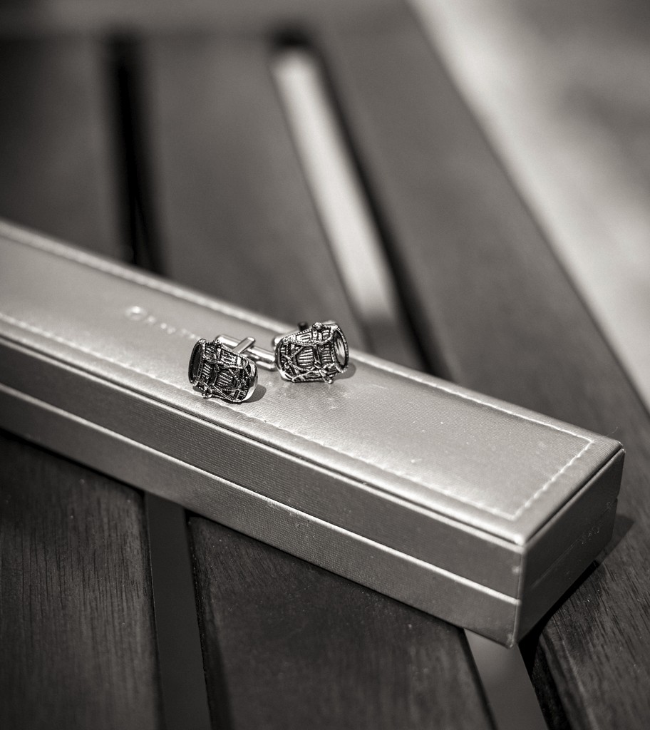 Elegant groom’s cufflinks on a golden box — refined wedding detail captured in soft daylight. Boutons de manchette élégants posés sur un écrin doré — détail raffiné de mariage capturé sous une lumière douce.