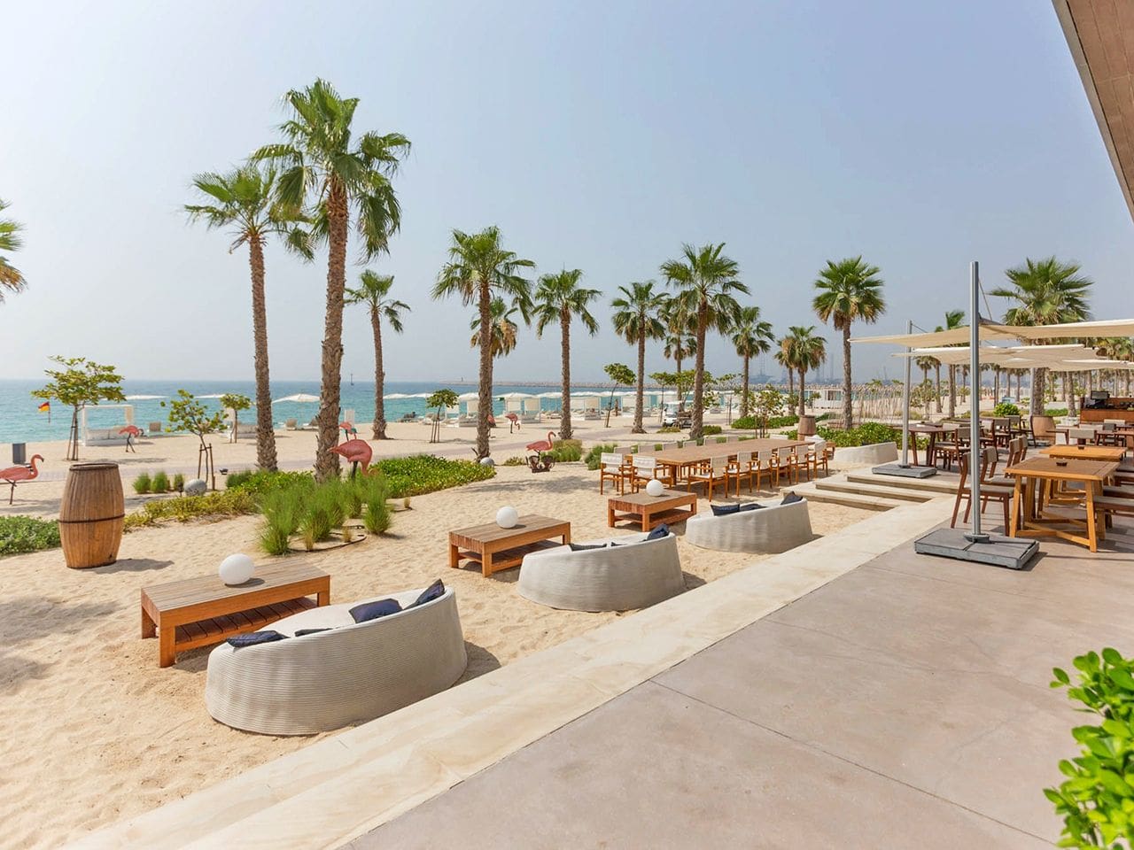 Beautiful Pearl Jumeirah beach showcasing gentle waves, sandy shores, and vibrant palm trees against a sunny backdrop.