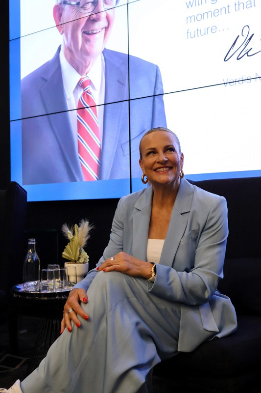 woman in blue suit sitting in a chair in front of a presentation