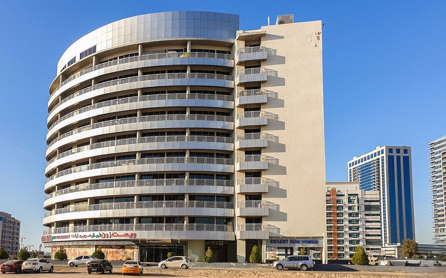 Row of contemporary sand-colored apartment buildings under a clear sky in Dubailand Residence Complex.