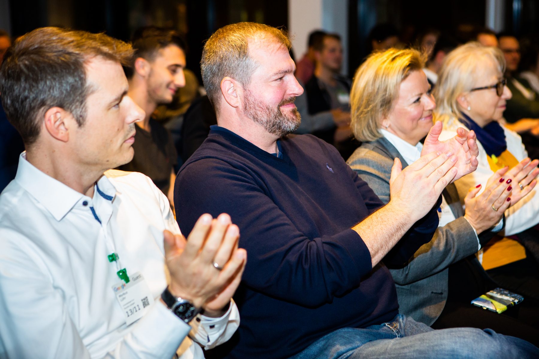 Die Leute sitzen in einem Konferenzraum und applaudieren - internetwarriors GmbH