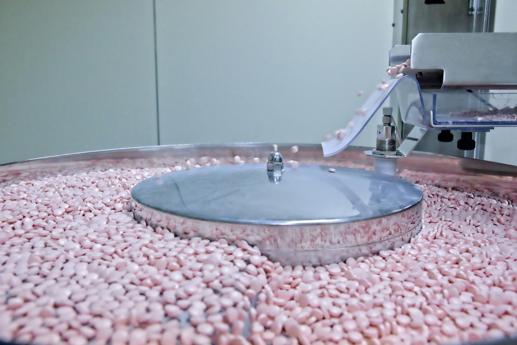 An employee inspecting gummy vitamins in a manufacturing facility, ensuring quality and safety compliance