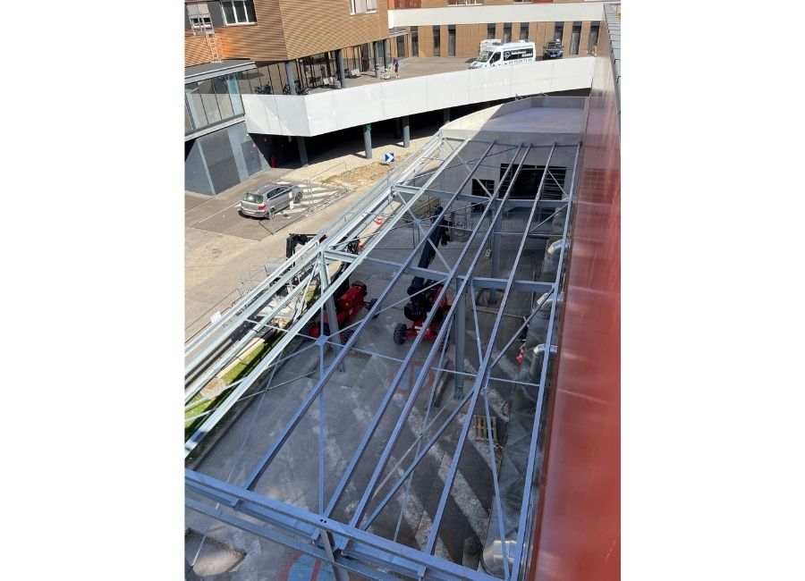 Vue plongeante sur l'intérieur d’un bâtiment en chantier, montrant les poutres métalliques.