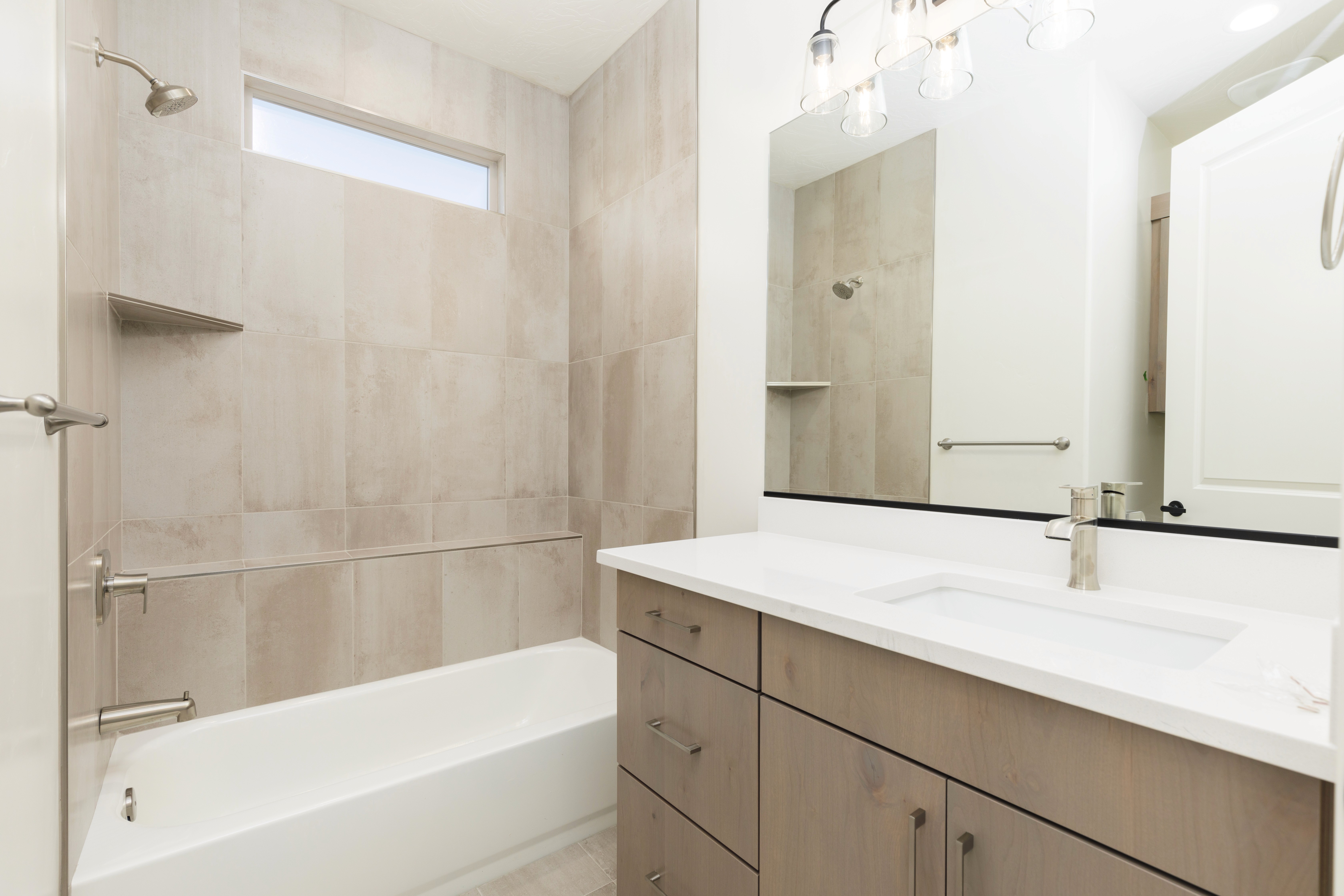 Hurricane, Utah home bathroom in Mountain View’s Cove featuring a tub with tiled surround and modern fixtures.