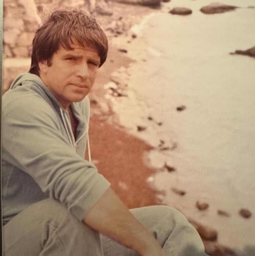 Portrait of Ferdinand "Fred" DeRubeis, a handsome man sitting on a beach