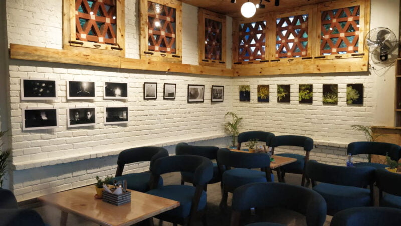 Intimate and artistic: White brick walls serve as a textured canvas for black-and-white photography, creating a sophisticated backdrop for the cozy blue lounge seating.