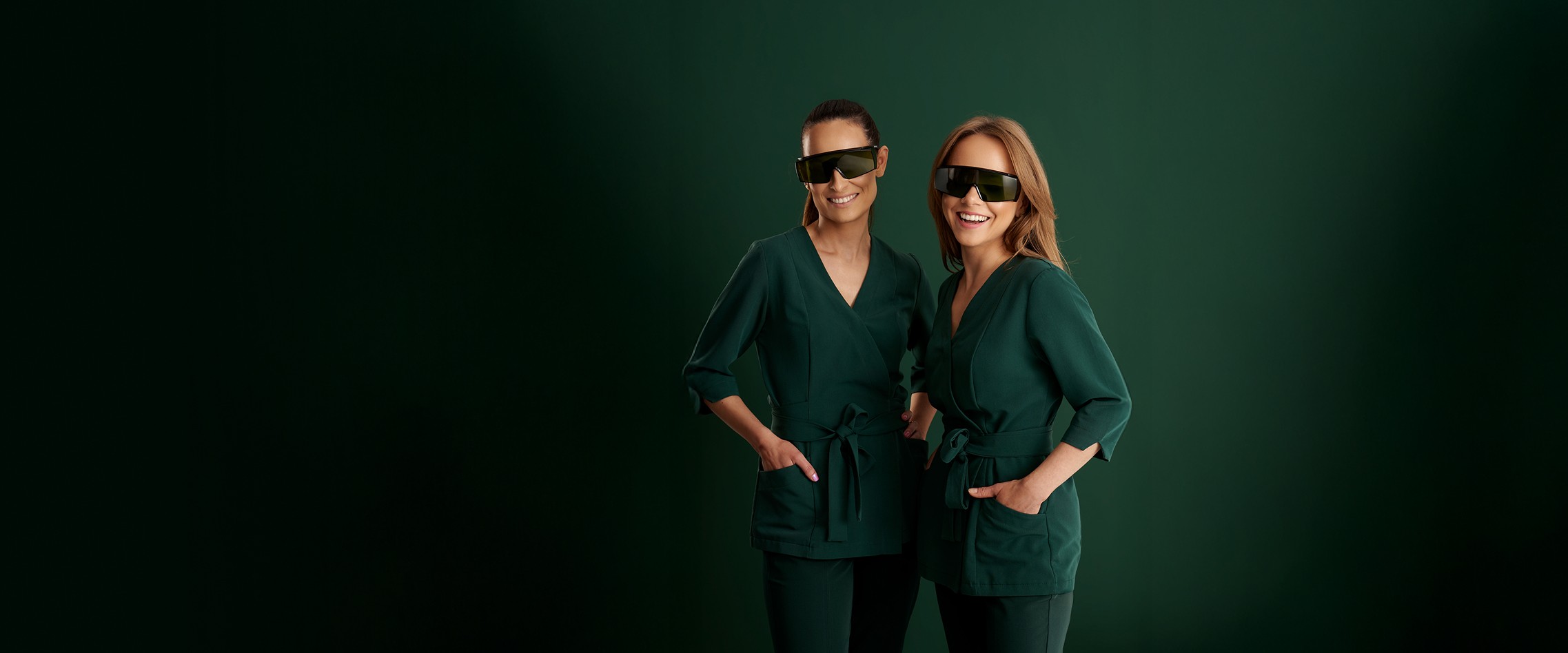 Two women stand next to each other in green suits