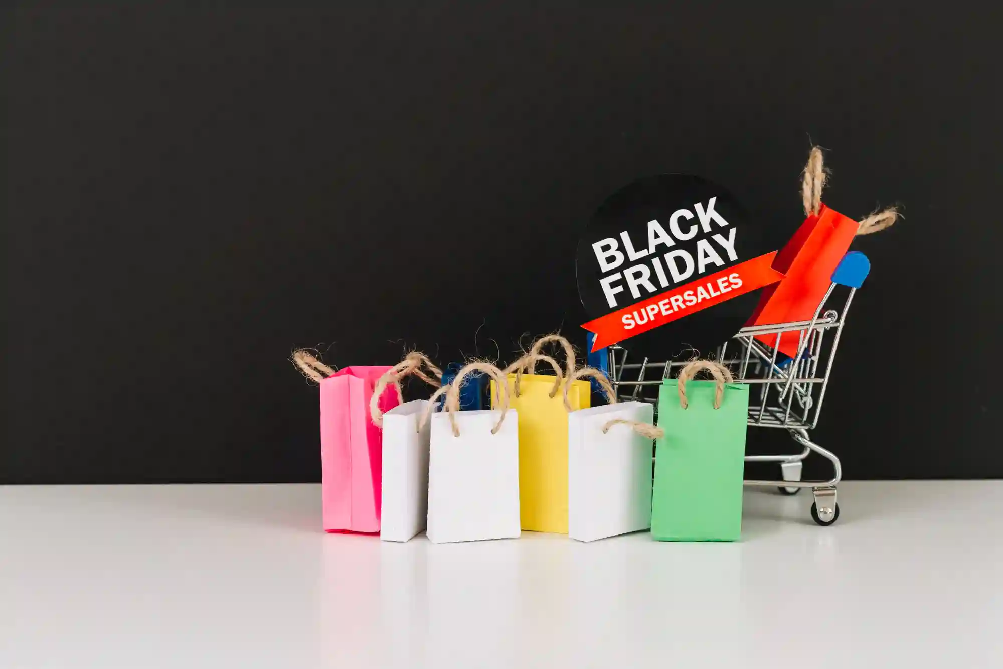 Miniature shopping cart with colorful bags and a "Black Friday Super Sale" sign, representing consumerism or e-commerce.