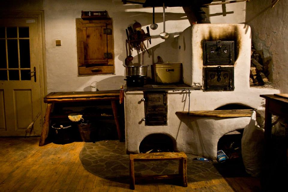 A smiling young man with crossed arms, wearing a plaid shirt and white t-shirt, poses against a dark background.