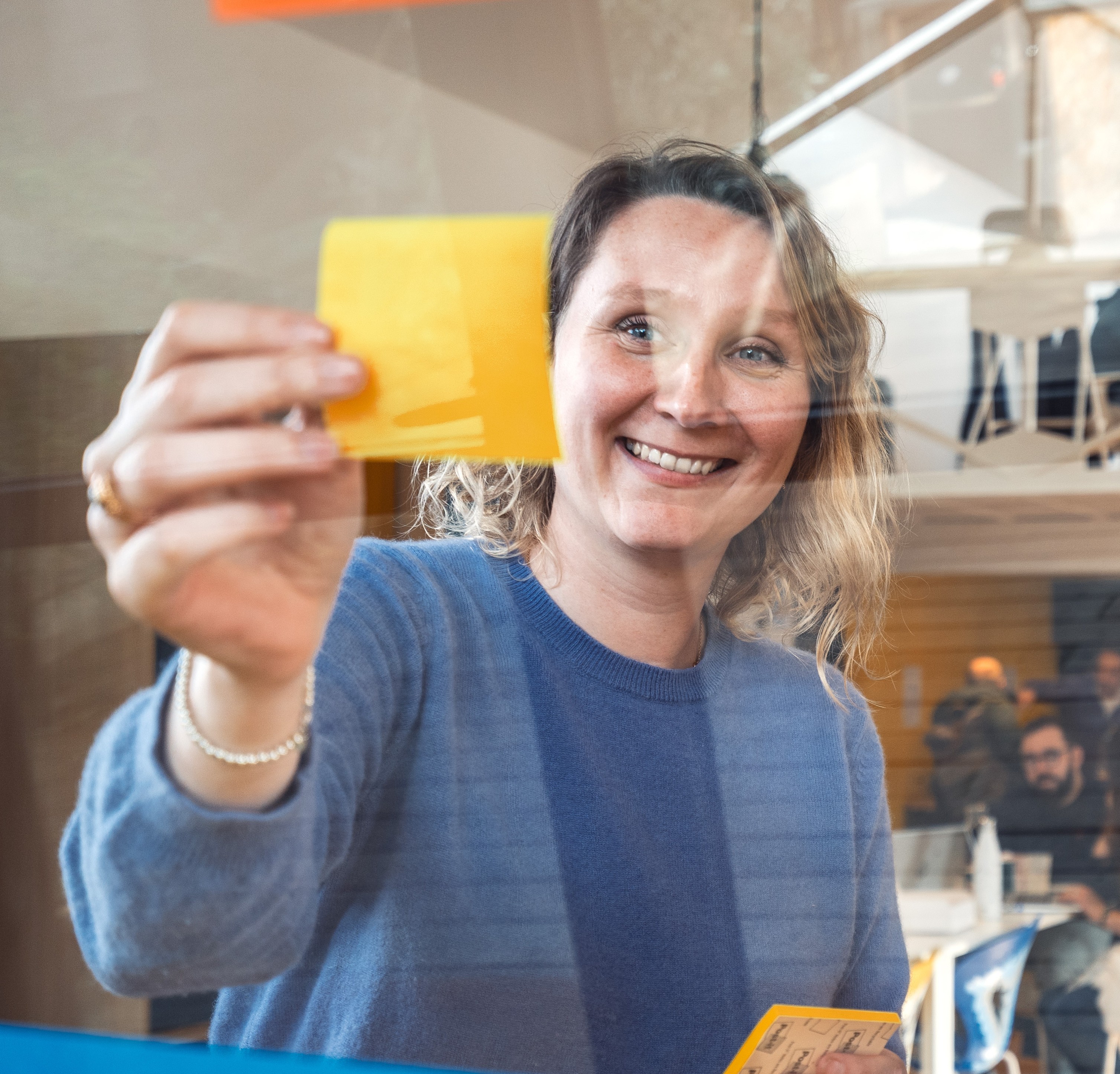 une femme en train de coller un post it sur une paroi transparente