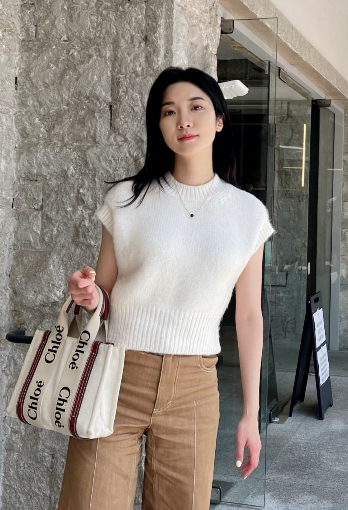 asian woman with white shirt and brown pants holding a bag