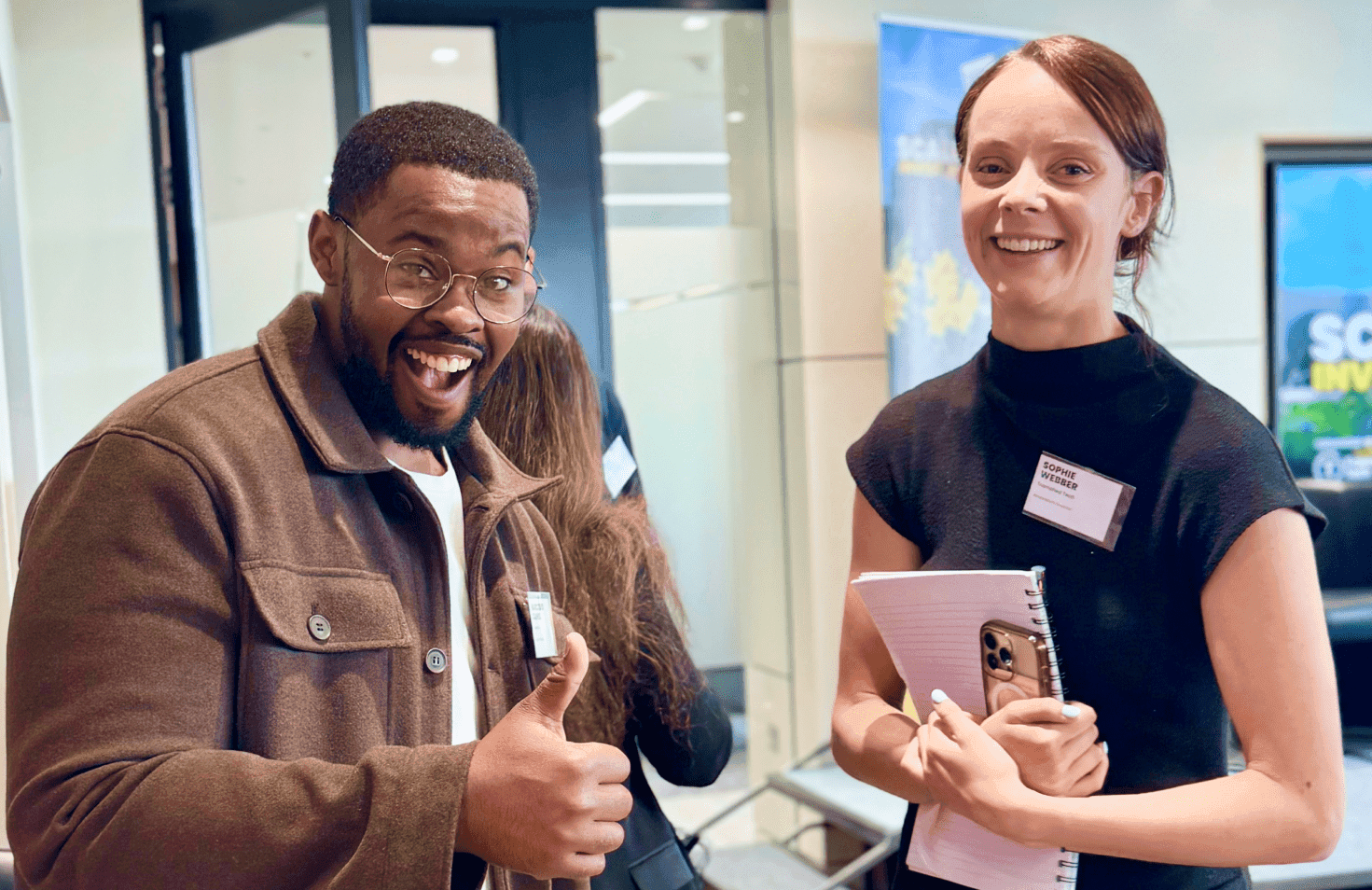 Person holding a paper at an event with another person nearby.