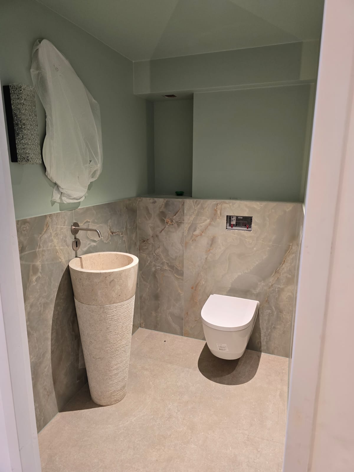 Vue large de la même salle de bains mansardée : baignoire îlot, paroi pierre sombre, spots plafond.