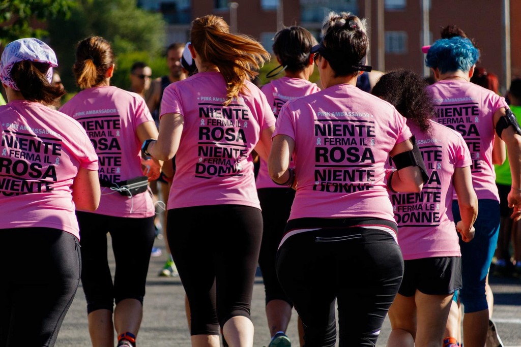 Group of women running in pink charity event t-shirts with inspirational messages.