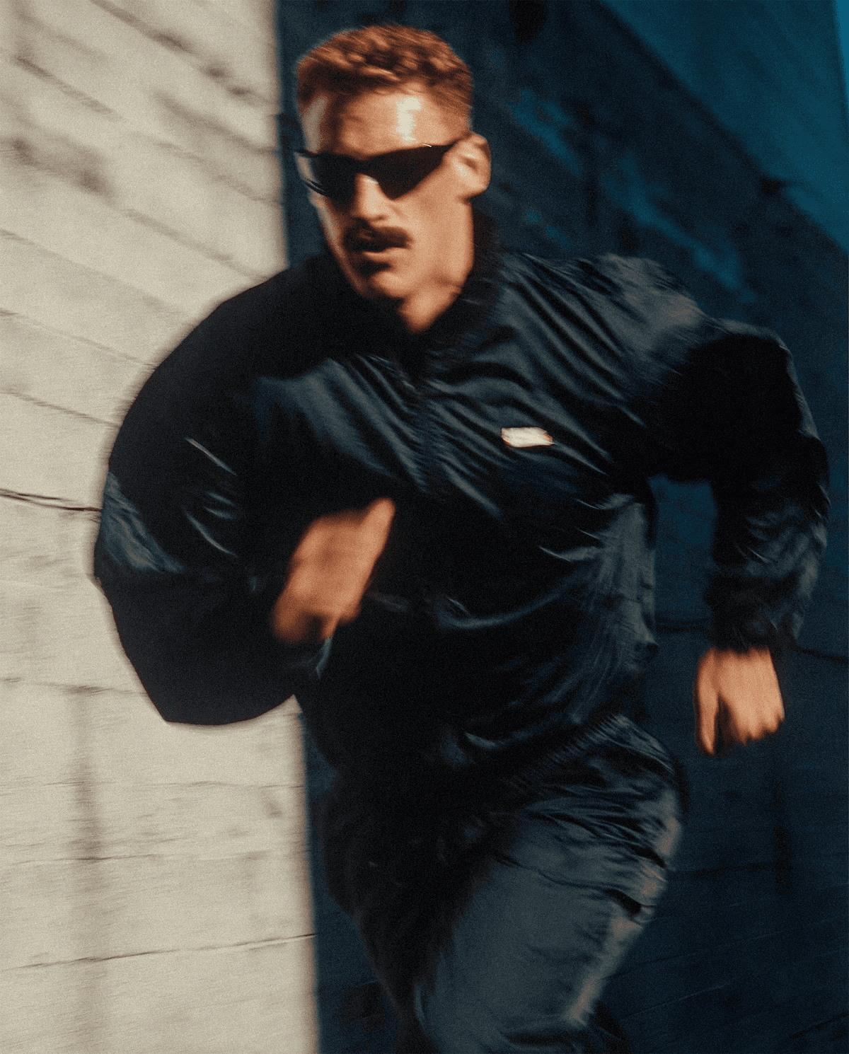 man wearing grey t-shirt standing in front of man sitting on chair