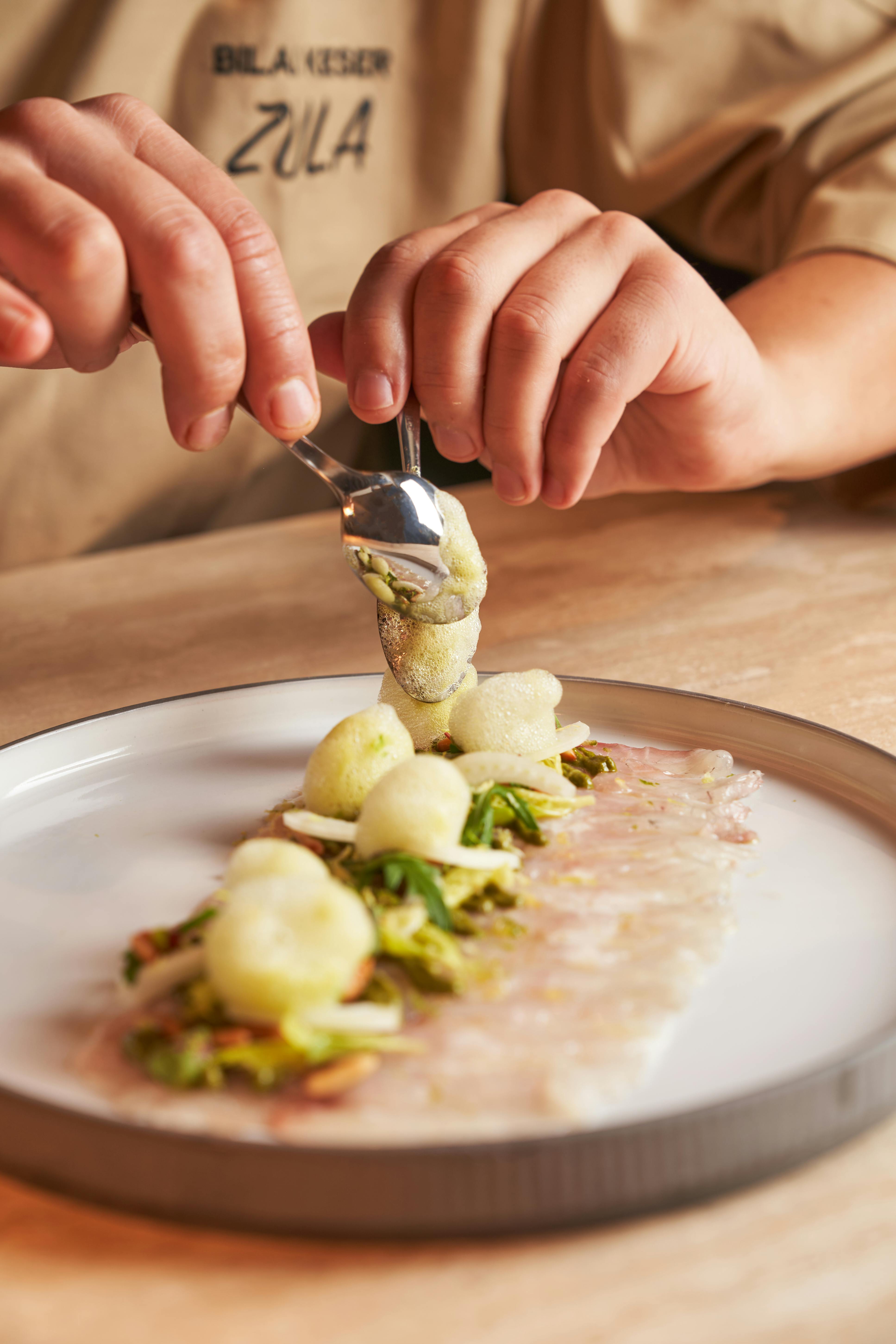 Assiette gastronomique et mains qui dressent l'assiette