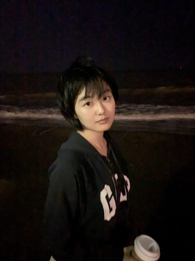 person looking at camera with short black hair and wearing a hoodie