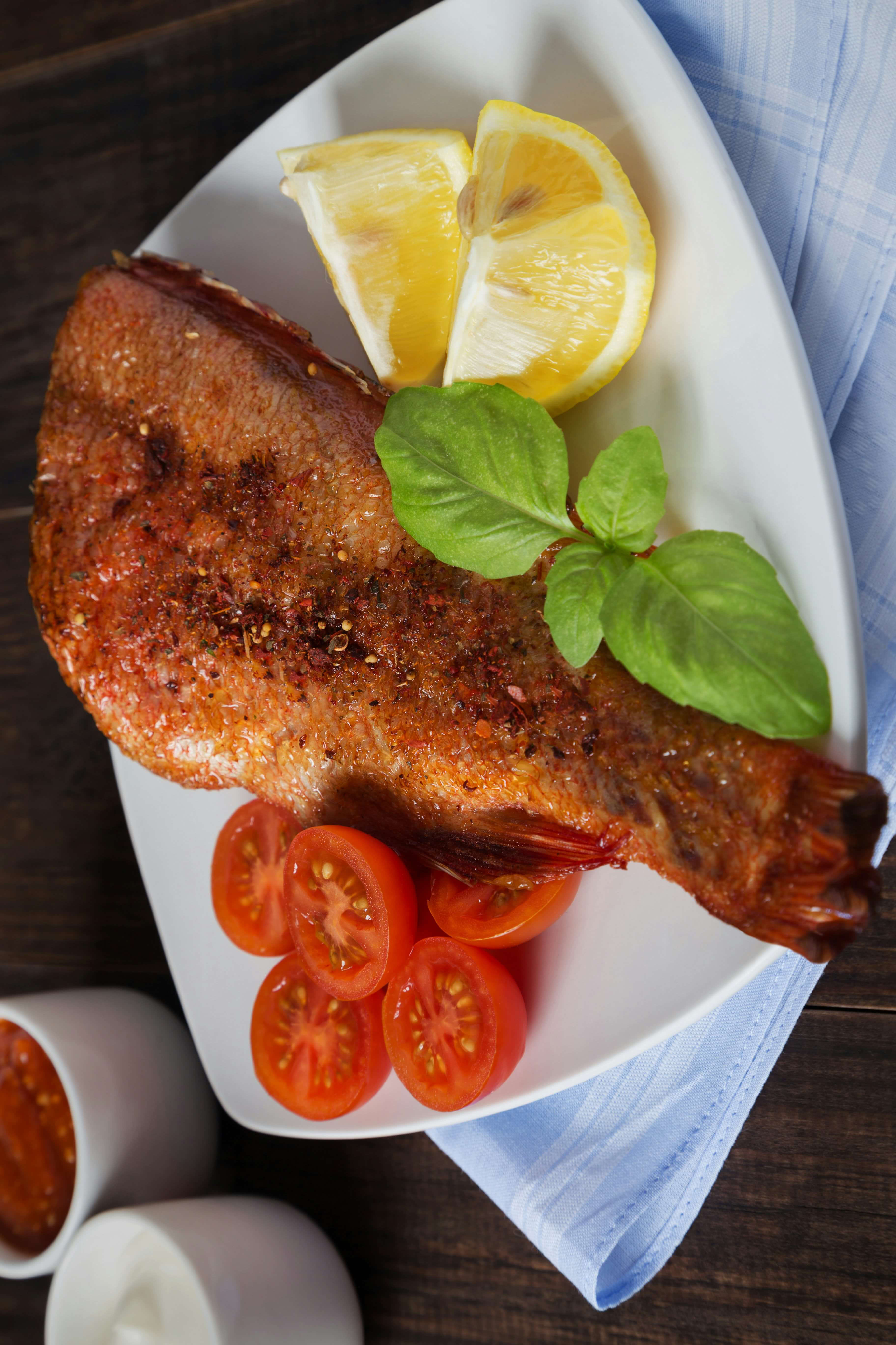 Grilled red snapper served with fresh tomatoes, lemon wedges, and herbs, showcasing Caribbean cuisine at Club Vieques.