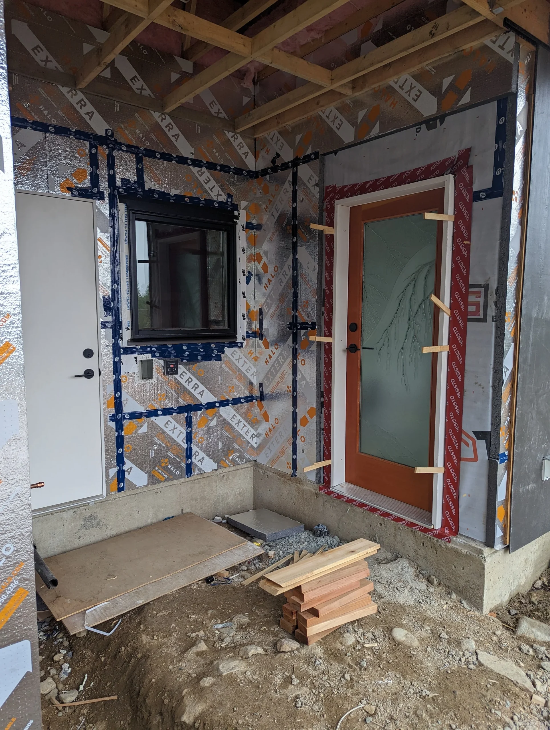 Modern two-story home with large glass windows, warmly lit interiors, and a balcony. Surrounded by trees and a manicured lawn at dusk. Cozy ambiance.