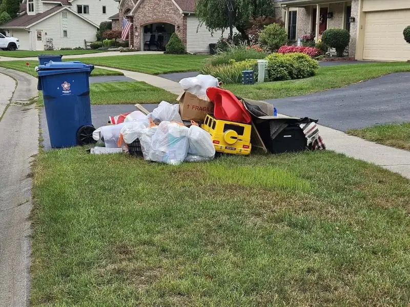 Before: pile of junk beside a blue trash can at the curb