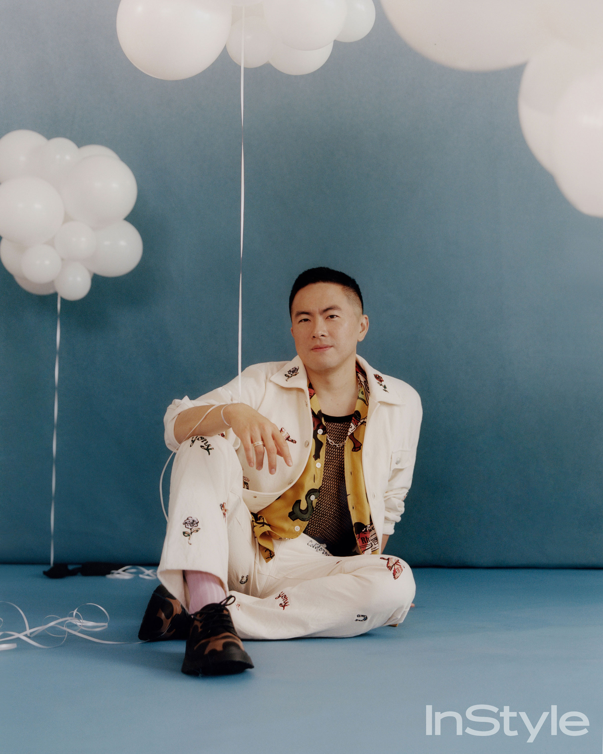 Bowen Yang seated among white balloon clouds for InStyle