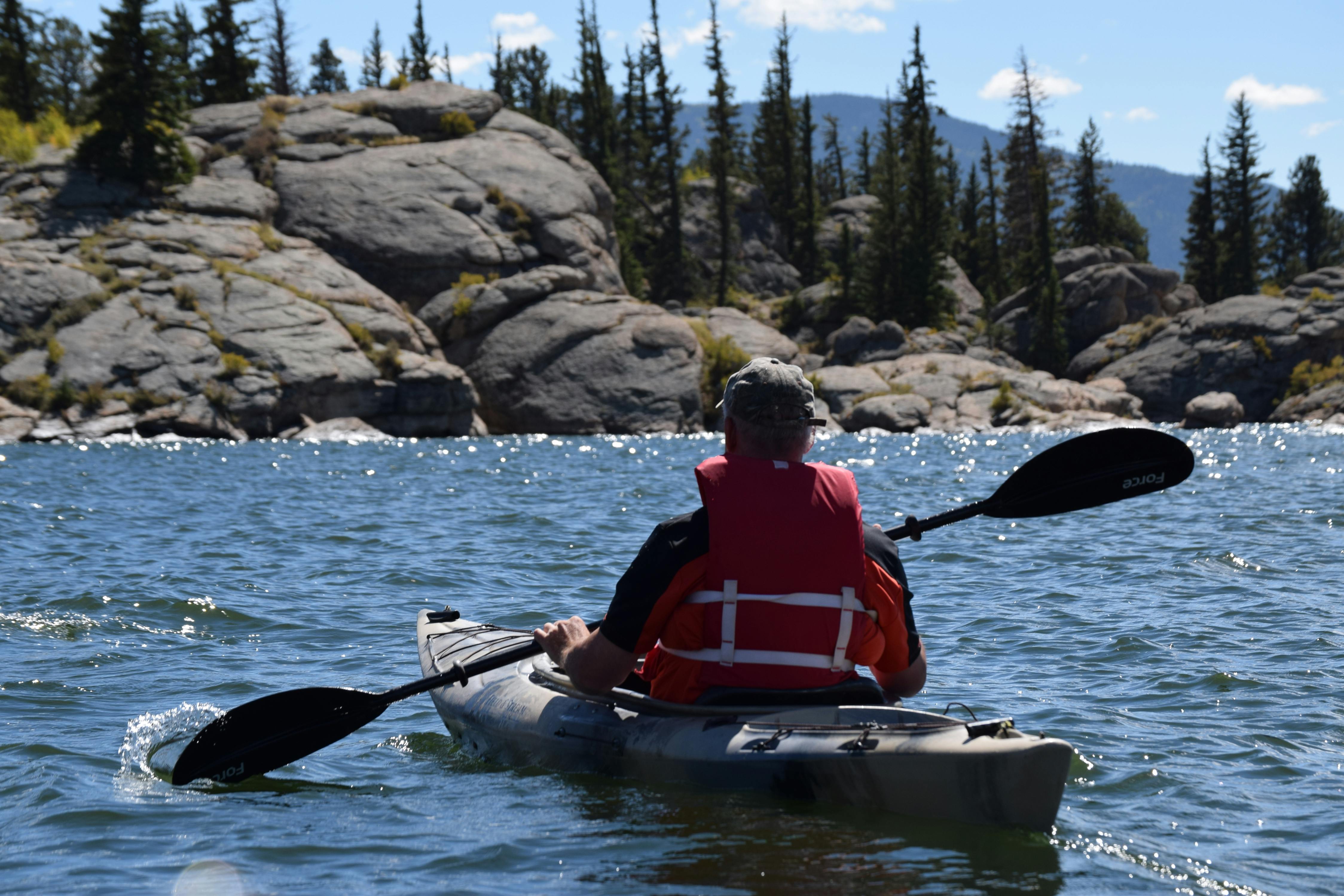 Un homme en veste rouge navigue sur un kayak